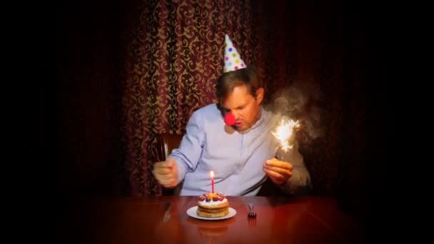 Ein einsamer Mann feiert ein Fest, er sitzt allein an einem Tisch mit einer Torte und einer Kerze. 4k, Zeitlupe — Stockvideo