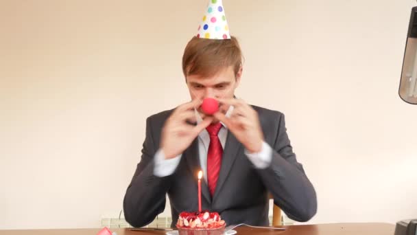 Yalnız bir adam bir tatil kutluyor, o yalnız bir kek ve bir mum ile bir masada oturuyor. 4k, ağır çekim — Stok video