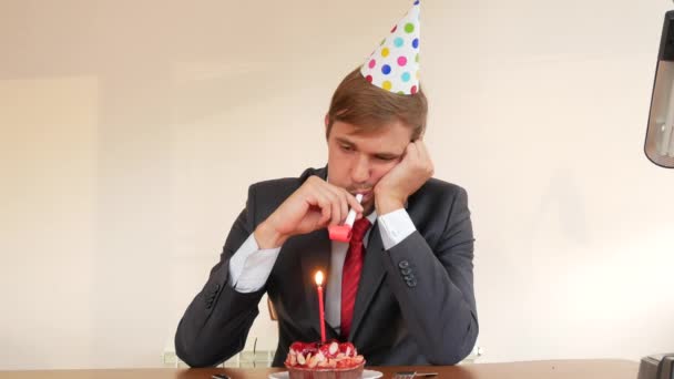 Un hombre solitario celebra una fiesta, se sienta solo en una mesa con un pastel y una vela. 4k, cámara lenta — Vídeos de Stock