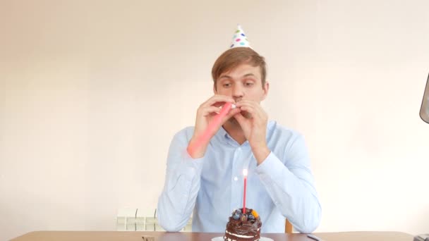 Ένας μοναχικός άνθρωπος γιορτάζει διακοπές, αυτός κάθεται μόνος σε ένα τραπέζι με μια τούρτα και ένα κερί. 4k, αργή κίνηση — Αρχείο Βίντεο