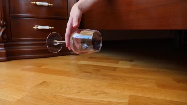 Close-up, vrouwelijke hand, het neerzetten van een glas rode wijn van het bed. de resten van wijn worden gegoten op de vloer. Slow motion — Stockvideo