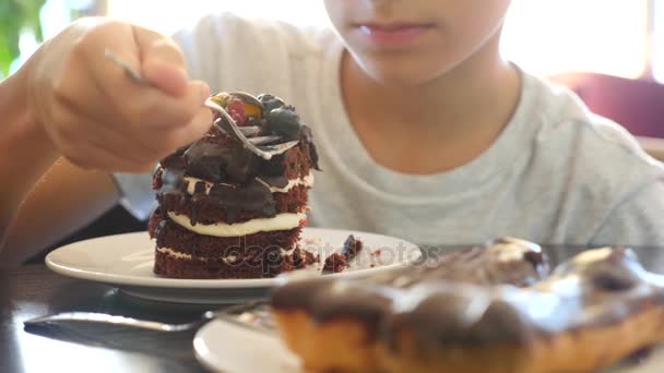Pojken i glasögon är att äta en läcker dessert i ett café. 4 k slowmotion — Stockvideo