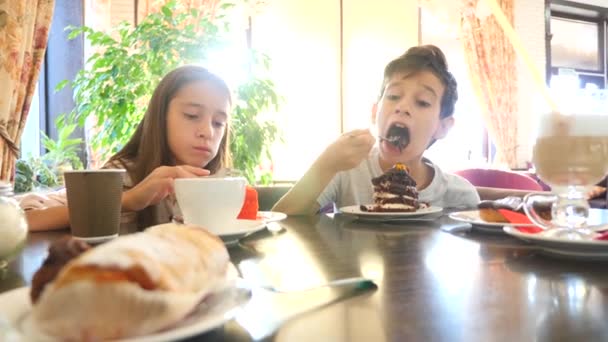 Niños, hermano y hermana, gemelos comen un delicioso postre en un café. 4k cámara lenta — Vídeo de stock