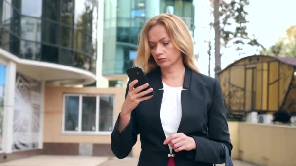 Geschäftsfrau im Business-Anzug mit Smartphone, zu Fuß auf einem Business Center, zu Fuß in der Stadt, Steadicam-Aufnahme. 4k, Zeitlupe, Kopierraum — Stockvideo