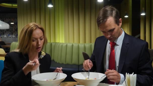 ビジネス パートナーの男性と女性は、カフェ利用のスマート フォンで昼食をとる。4 k コピー スペース — ストック動画