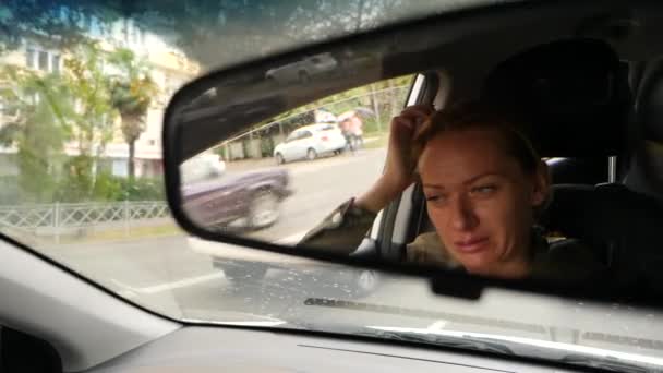 Отражение женского лица с голубыми глазами в зеркале заднего вида, женщина за рулем. 4k, slow motion — стоковое видео