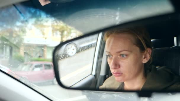 Отражение женского лица с голубыми глазами в зеркале заднего вида, женщина за рулем. 4k, slow motion — стоковое видео