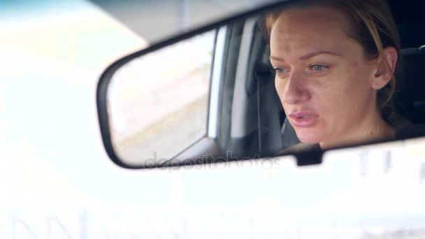 Reflejo de una cara de mujer con ojos azules en espejo retrovisor, mujer detrás del volante. 4k, cámara lenta — Vídeo de stock