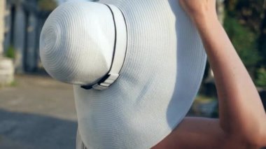 Güzel kadın styling saç açık havada. Çok yavaş hareket. Parkta eğleniyor, doğanın keyfini, Rüzgar ile oynarken mutlu sakin kız uzun saçlı. onun şapkasını alır.