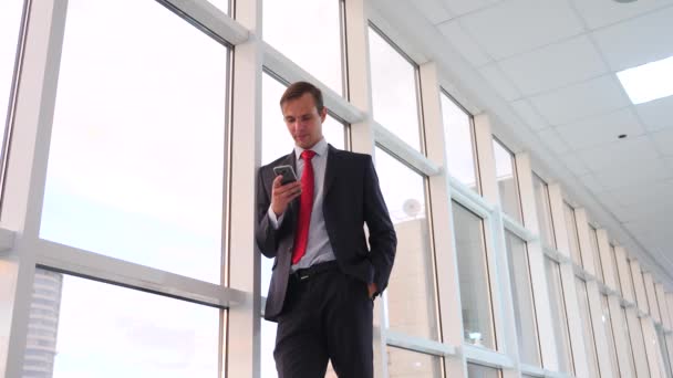 Podnikatel chůze a telefon v blízkosti panoramatické okno. Zpomalený pohyb, 4k — Stock video