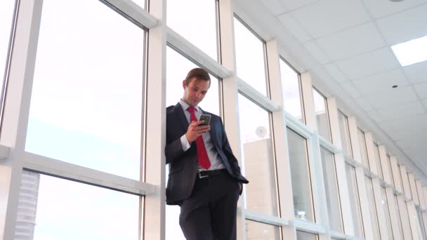 Man en vrouw in pakken staan en praten. Zakenman en zakenvrouw zijn in de office-corridor voor het raam. 4k, slow-motion — Stockvideo