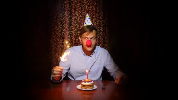 Un hombre solitario celebra una fiesta, se sienta solo en una mesa con un pastel y una vela. 4k, cámara lenta — Vídeos de Stock