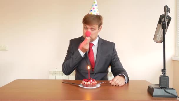 Um homem solitário celebra um feriado, ele se senta sozinho em uma mesa com um bolo e uma vela. 4k, câmera lenta — Vídeo de Stock