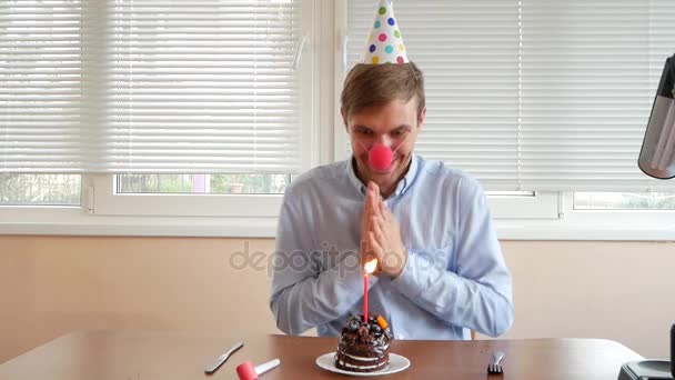 Um homem solitário celebra um feriado, ele se senta sozinho em uma mesa com um bolo e uma vela . — Vídeo de Stock