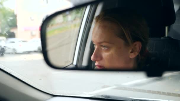 Reflectie van het gezicht van een vrouw met blauwe ogen in de achteruitkijkspiegel, vrouw achter het stuur. 4k, slow-motion — Stockvideo