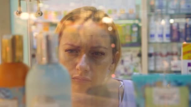 A mulher olha para os medicamentos na janela da farmácia. 4k, câmera lenta — Vídeo de Stock
