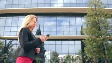 bir iş merkezi city, steadicam atış yürüme yürüyüş iş kadını bir smartphone ile iş takım elbiseli. 4k, ağır çekim, alanı Kopyala