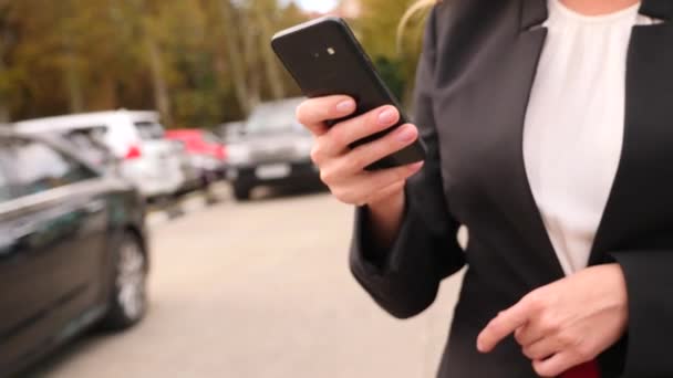 Mujer de negocios en un traje de negocios con un teléfono inteligente, caminando en un centro de negocios, caminando en la ciudad, steadicam tiro. 4k, cámara lenta, espacio para copiar — Vídeos de Stock