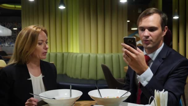 Socios de negocios hombre y mujer almorzar en la cafetería uso de teléfonos inteligentes. Espacio de copia 4K — Vídeos de Stock