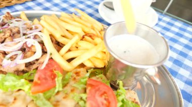 yakın çekim, mens eller Yunan souvlaki ye. Patates kızartması bir parçası haline bir beyaz sos dips. 4k, ağır çekim