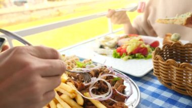 romantik bir çift, bir açık kafe Yunan yemekleri yemek kahvaltı souvlaki ve bir Yunan. 4k, ağır çekim