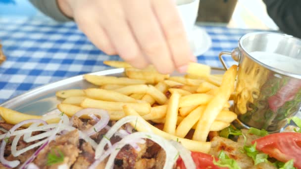 Primo piano, le mani degli uomini mangiano souvlaki greci. immerge un pezzo di patatine fritte in una salsa bianca. 4k, rallentatore — Video Stock