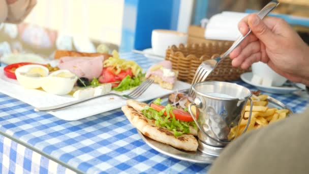Ρομαντικό ζευγάρι τρώει σε ένα υπαίθριο καφέ Ελληνικά πιάτα, με σουβλάκι και ένα ελληνικό πρωινό. 4k, αργή κίνηση — Αρχείο Βίντεο