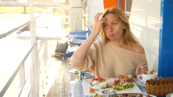 Καυκάσιος γυναίκα τρώει ένα παραδοσιακό ελληνικό πρωινό σε ένα υπαίθριο καφέ. 4k, αργή κίνηση — Αρχείο Βίντεο
