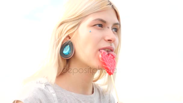 Bodymification. a girl with a split tongue licks lollipop. 4k, slow-motion shooting, copying space — Stock Video