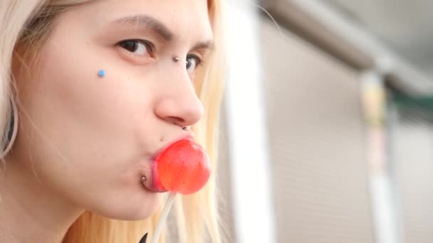 Bodymification. een meisje met een gespleten tong likt lollipop. 4k, slow-motion-video schieten, kopiëren ruimte — Stockvideo