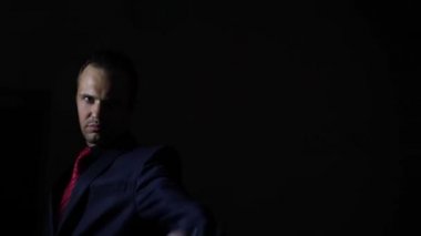 Karanlıkta silahını çekerek ve kameraya hedefleyen bir adam. 4k, ağır çekim