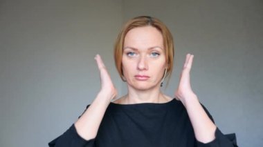 4 k. yakın çekim parlak mavi gözlü güzel sarışın kadının. genç bir kadın portresi. beden dili ve hareketleri. o elleriyle kulaklarını kapatır, dinlemek istemiyor.