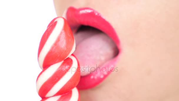 Сексуальная девушка ест леденец. имитация орального секса. язык облизывает конфеты. 4К, замедленная съемка, крупный план. копировальное пространство — стоковое видео
