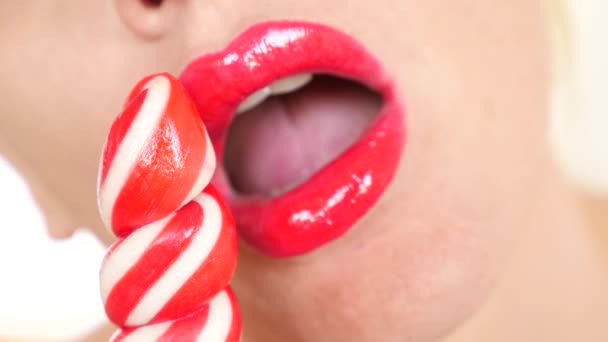 Сексуальная девушка ест леденец. имитация орального секса. язык облизывает конфеты. 4К, замедленная съемка, крупный план. копировальное пространство — стоковое видео