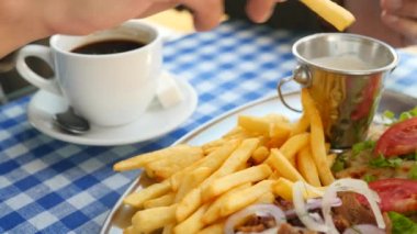 yakın çekim, mens eller Yunan souvlaki ye. Patates kızartması bir parçası haline bir beyaz sos dips. 4k, ağır çekim