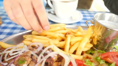 yakın çekim, mens eller Yunan souvlaki ye. Patates kızartması bir parçası haline bir beyaz sos dips. 4k, ağır çekim
