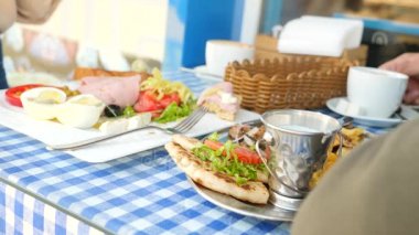 romantik bir çift, bir açık kafe Yunan yemekleri yemek kahvaltı souvlaki ve bir Yunan. 4k, ağır çekim