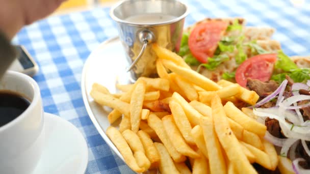 Primer plano, las manos de los hombres comen souvlaki griego. sumerge un trozo de papas fritas en una salsa blanca. 4k, cámara lenta — Vídeos de Stock