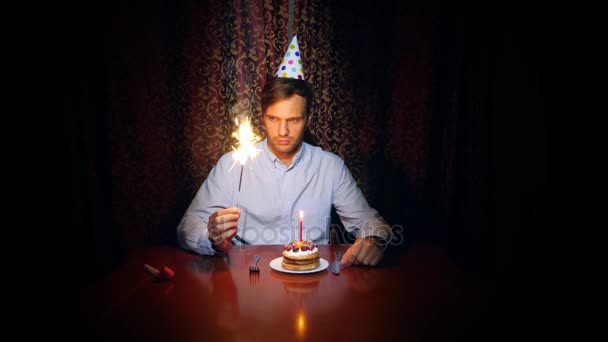 Ein einsamer Mann feiert ein Fest, er sitzt allein an einem Tisch mit einer Torte und einer Kerze. 4k, Zeitlupe — Stockvideo