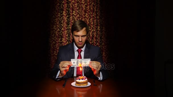 Een eenzame man een vakantie viert, hij zit alleen aan een tafel met een taart en een kaars. 4k, slow-motion — Stockvideo