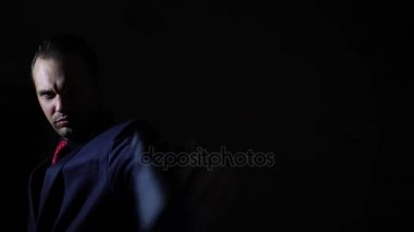 Karanlıkta silahını çekerek ve kameraya hedefleyen bir adam. 4k, ağır çekim