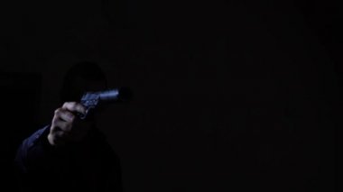 Karanlıkta silahını çekerek ve kameraya hedefleyen bir adam. 4k, ağır çekim