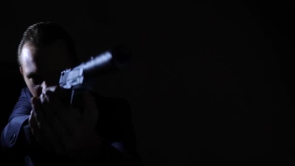 Homem puxando sua arma na escuridão e apontando para a câmera. 4k, câmera lenta — Vídeo de Stock