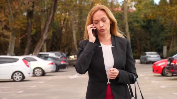 Деловая женщина в деловом костюме со смартфоном, гуляет по бизнес-центру, гуляет по городу, стадикам застрелен. 4k, slow motion, copy space — стоковое видео