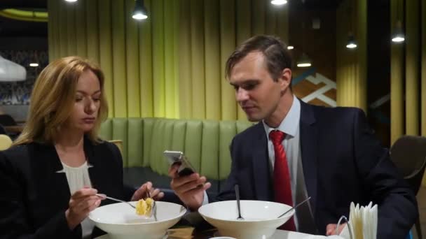 Business partners man and woman have lunch at cafe use smartphones. 4K copy space — Stock Video