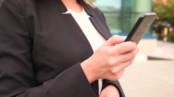 Business woman in a business suit with a smartphone, walking on a business center, walking in the city, steadicam shot. 4k, slow motion, copy space — Stock Video