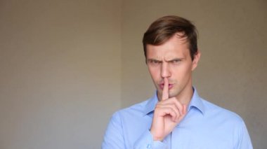 4 k. ağır çekim. Genç bir adam portresi kapatın. beden dili ve hareketleri. o dudaklar için daha sessiz parmağını koyar.