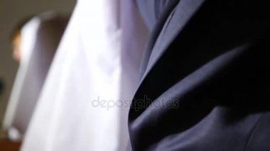 bir adam bir iş takım elbise ve kravat beyaz bir elbise giyiyor. 4k, ağır çekim