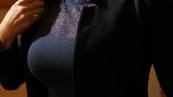 Μια γυναίκα με ένα όμορφο στήθος τοποθετεί σε ένα μαύρο σακάκι. 4k, αργή κίνηση — Αρχείο Βίντεο