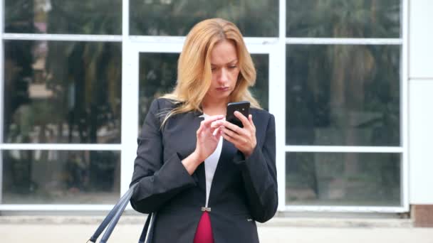 Деловая женщина в деловом костюме со смартфоном, гуляет по бизнес-центру, гуляет по городу, стадикам застрелен. 4k, slow motion, copy space — стоковое видео